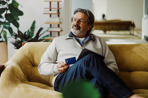 Grey-haired shopping senior man pays with a credit card