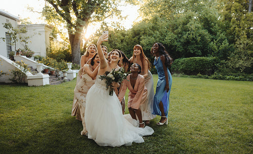 Bride and bridesmaids taking a selfie outdoors during a beautiful wedding celebration