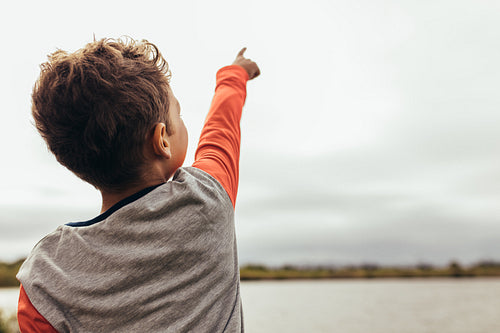 Portrait of a boy pointing towards the sky