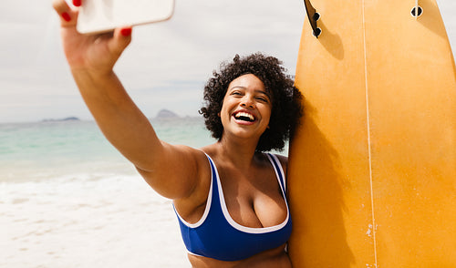 Happy young woman surfer captures beach adventure with a selfie