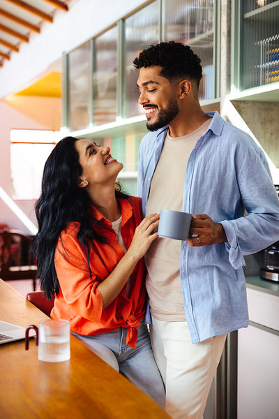 Happy Latin American couple enjoying coffee together in a stylish modern kitchen