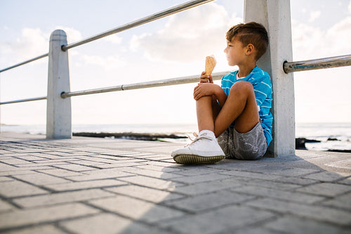 Boy eating an ice cream sitting near seashore