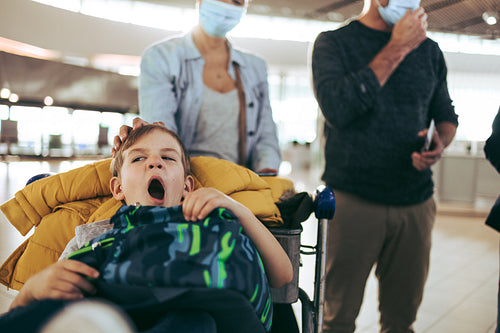 Boy with family at airport feeling tired