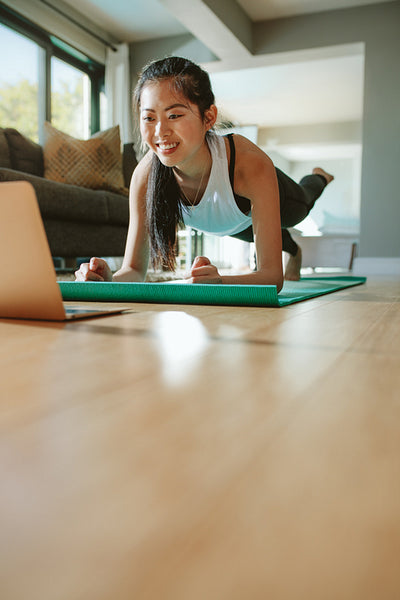 Woman doing exercise and watching tutorial lesson on laptop