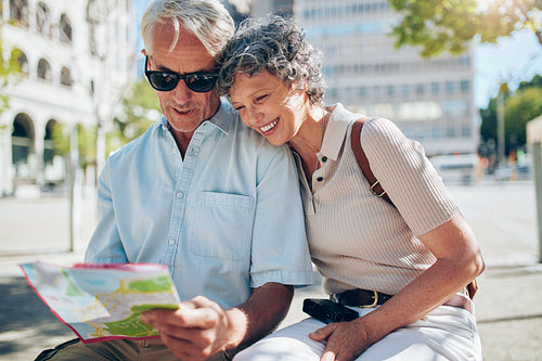 Happy senior tourists looking at a city map
