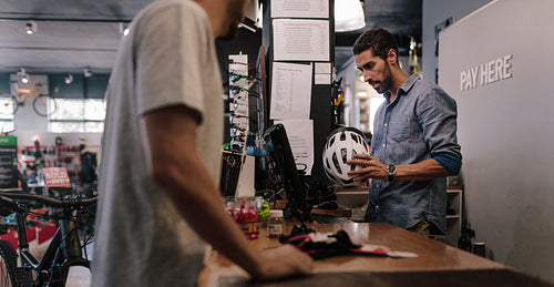 Shop owner selling helmet to customer