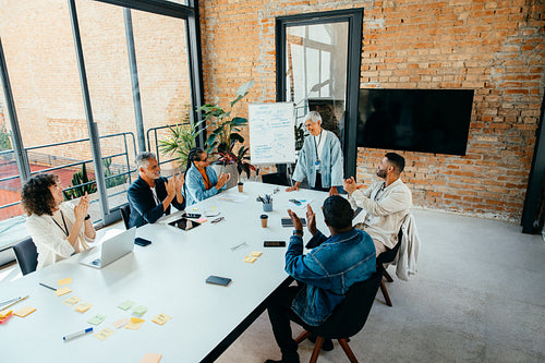 Successful meeting of diverse business colleagues engaged in a productive discussion around a bright, modern conference room