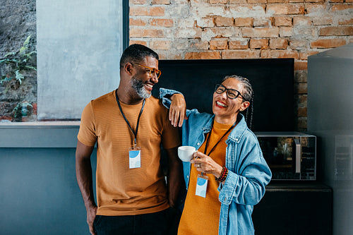 Smiling colleagues taking a break and enjoying a relaxed conversation with coffee