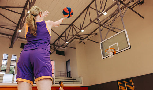 Female basketball player shooting the ball during practice in indoor gym