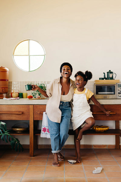 Happy mother and daughter enjoying morning coffee in the kitchen