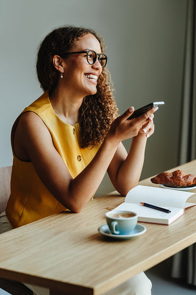 Woman holding a phone during a coffee break at the table