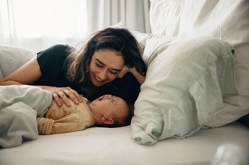 Mother cuddling her tired baby in bed