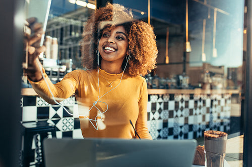 Smiling woman sitting at a cafe taking a selfie