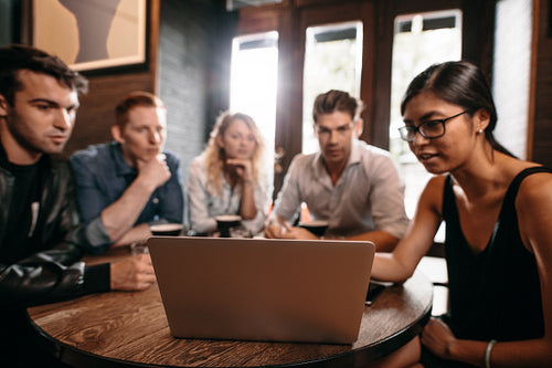 Group of friends at cafe using laptop