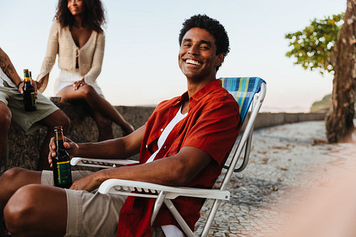 Young Brazilian man relaxing on a deck chair at Urca’s Wall
