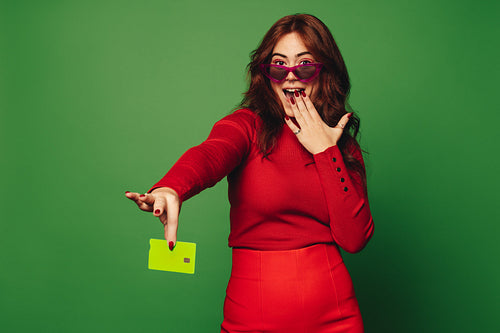 Happy woman paying with a sustainable and contactless credit card on a vibrant green background