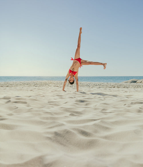 Woman in bikini upside down on beach