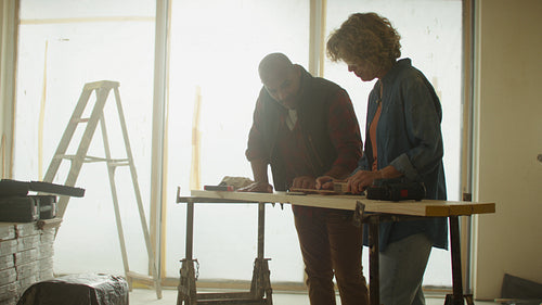 Designing together: Mature couple measuring and preparing wood