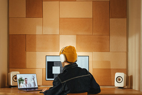 Man uses dual monitors and headphones for video call at  office desk