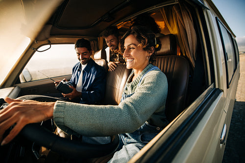 Friends on a road trip in a sunny van smiling as they drive together