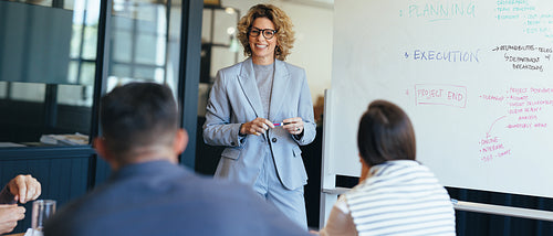 Business woman standing in front her team discussing her ideas. Business team having a meeting in a boardroom