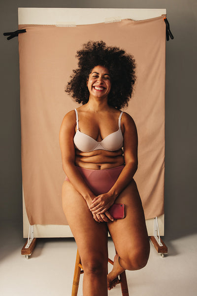 Happy woman with an Afro hairstyle wearing underwear in a studio