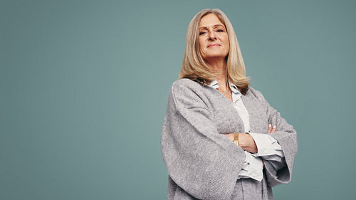 Cross-armed mature woman standing in a studio