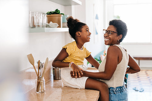 Happy mother-daughter moments: Girl laughing with her mom in the kitchen