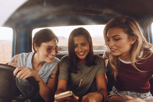 Girls traveling by a car and looking at phone