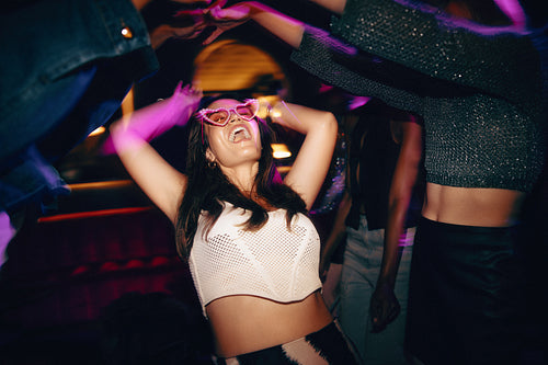 Young woman celebrating at party with vibrant lights and joyful atmosphere