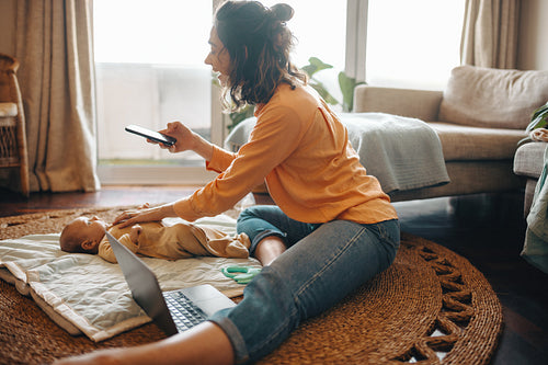 Mother taking pictures of baby at home on rug