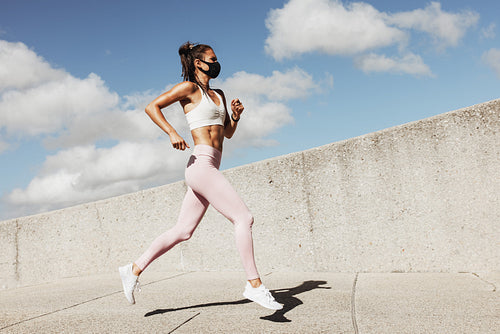 Sports woman wearing face mask running outdoors