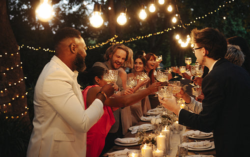 Outdoor wedding celebration with friends under string lights during an intimate dinner