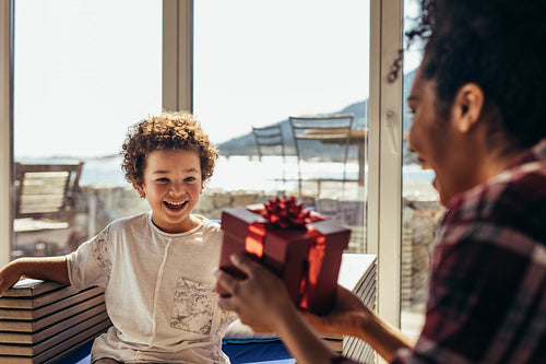 Mother giving a gift to her child at a beach house