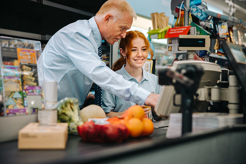 Grocery store manager training a new cashier