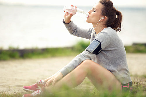 Female Jogger Resting and Drinking Bottled Water