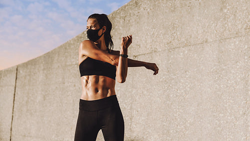 Woman with face mask doing warm up workout
