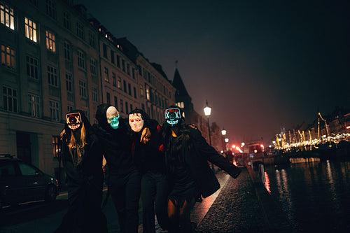 Group of friends wearing glowing masks at night in urban settings