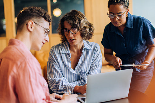 Three colleagues discussing work plans together in a modern office environment