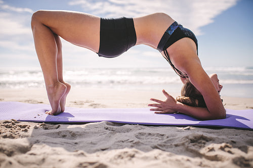 Woman doing yoga backbends on the beach