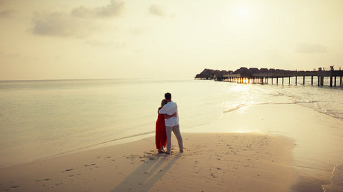 Romantic couple embraces on a stunning tropical beach during a beautiful sunset vacation