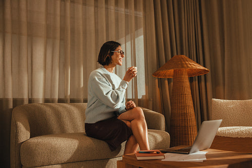Woman takes a coffee break from work in her private office on a sofa