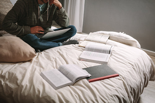 Student studying for exams using laptop and books