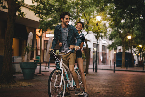Loving couple riding bicycle on city road