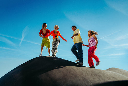 Friends embrace adventure on a hill under a blue sky