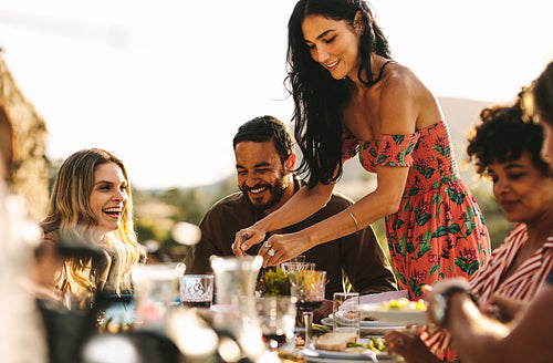 Beautiful woman serving food to friends