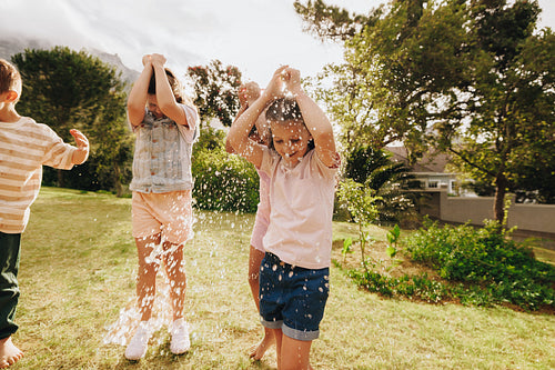 Children playing with water in a sunny backyard during summer