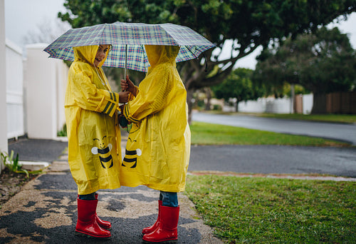 Little girls with raincoats and umbrella outdoors on a rainy day