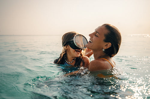 Mother and child swimming at sunset on a tropical island