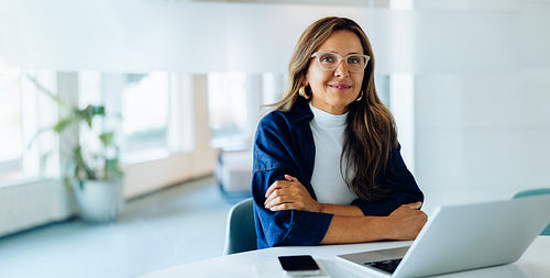 Woman at laptop in office smiles confidently
